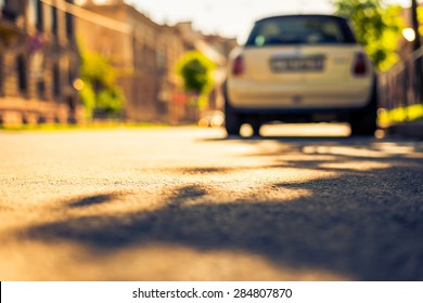 City On A Sunny Day, A Quiet Street With Trees And Parking Car. View From The Level Of Asphalt, Image In The Yellow-blue Toning