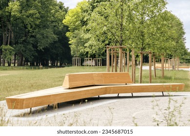 City Park with Wood Modern Park Bench and Young Trees. New Relax Area with Landscaping. Eco City Landscape concept. - Powered by Shutterstock