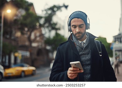 City, phone and man listening to music, podcast and jazz to travel on work commute in winter. Mobile, outdoor and person streaming audio on headphones for online subscription or scroll social media - Powered by Shutterstock