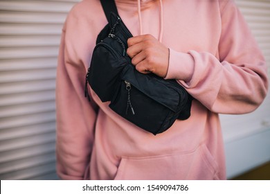 City portrait of handsome hipster guy wearing pink blank hoodie with black waist bag with space for your logo or design. Mockup for print