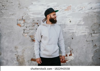 City portrait of handsome hipster guy with beard wearing gray blank hoodie and baseball cap with space for your logo or design. Mockup for print - Powered by Shutterstock