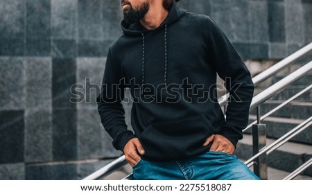 City portrait of handsome hipster man with beard wearing black blank hoodie with space for your logo or design. Mockup for print