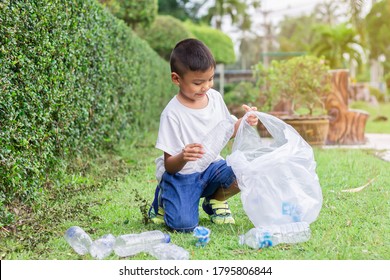 At The City Public Park. Asian Child Boy Is A Volunteer For Clean Up The Field Floor. He Picking Up Many Plastic Bottle And Straw On The Ground. Save Environmental And Reduce Waste Concept.