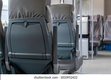 City railroad express train interior. Rows of grey seats with folding tables. Glass partition with grey vertical handrails in aisle. Empty coach of passenger railroad transportation with copy space - Shutterstock ID 1810952422