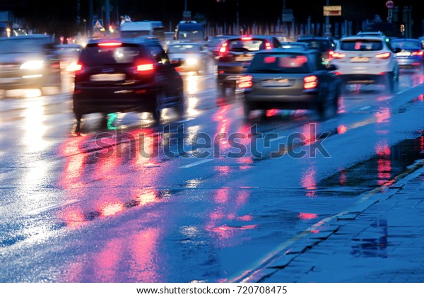 city road during rain. cars driving on wet
road with headlights.