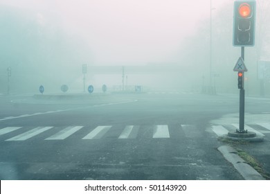 City Road Intersection Roundabout In Mist Fog. Traffic Light Showing Red. Misty Magic Concept Wallpaper. 