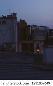 The City Rooftops At Dawn, Blue Hour With One Window Lit. 