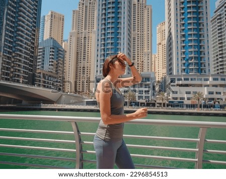 City Running - asian woman runner , Dubai marina urban scene in background. Female athlete, fitness athlete jogging training, living healthy lifestyle.