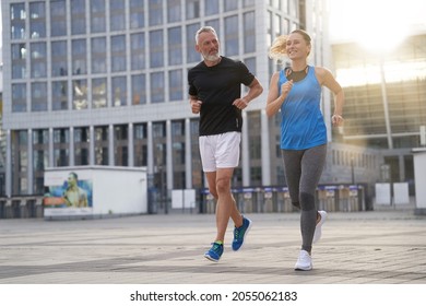 City Running Middle Aged Couple Jogging Together In The Morning While Training Outdoors