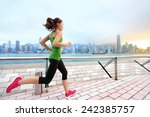 City Running - woman runner and Hong Kong skyline. Female athlete fitness athlete jogging training living healthy lifestyle on Tsim Sha Tsui Promenade and Avenue of Stars in Victoria Harbour, Kowloon.