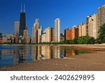The city skyline of Chicago is reflected in the still water of Lake Michigan