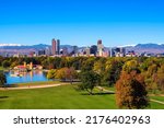 City skyline of Denver Colorado downtown with snowy Rocky Mountains and the City Park Lake.