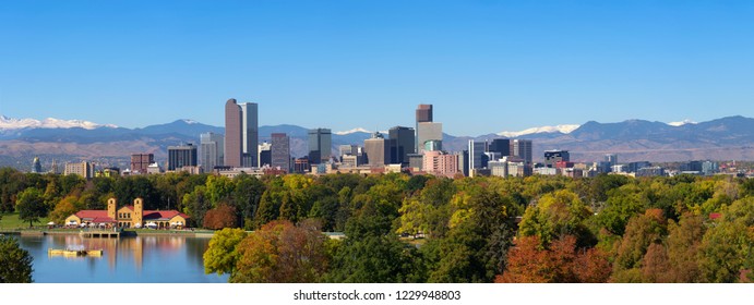 City skyline of Denver Colorado downtown with snowy Rocky Mountains and the City Park Lake. Large panorama.