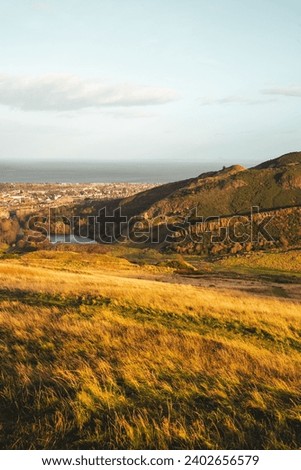 The city skyline of Edinburgh from a grassy hilltop.