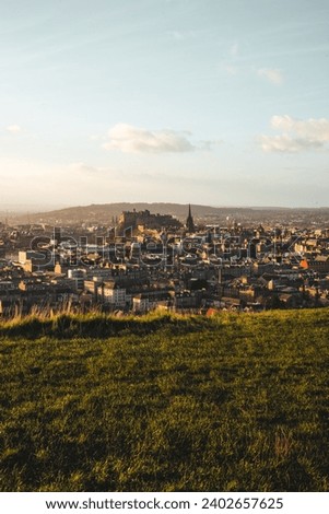 The city skyline of Edinburgh from a grassy hilltop.