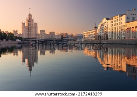 City skyline with empire style skyscraper on a riverbank at sunrise, Moscow, Russia