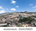 City sprawling across a hillside under a bright blue sky.