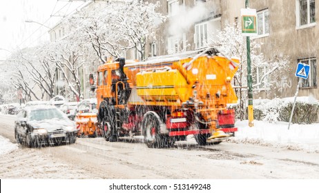 City Street Covered With Snow During Heavy Winter Storm In One European Capital City, Vehicles Defocused Due To Its Movement, Snowplough Shoveling Roads