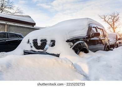 City Street Driveway Parking Lot Spot With Small Car Covered Snow Stuck Trapped After Heavy Blizzard Snowfall Winter Day By Big Snowy Pile. Snowdrifts And Freezed Vehicles. Extreme Weather Conditions