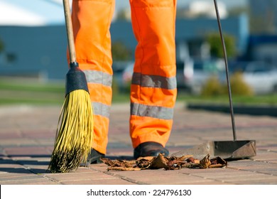 City street male or female sweeper cleaning pavement with broom tool