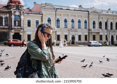 City Summer Vacation, urban trip with audio guide. Audio Tours and Exploring new places. Hipster woman traveler with dreadlocks headphones and cell phone use audio guide and Audio Tours app