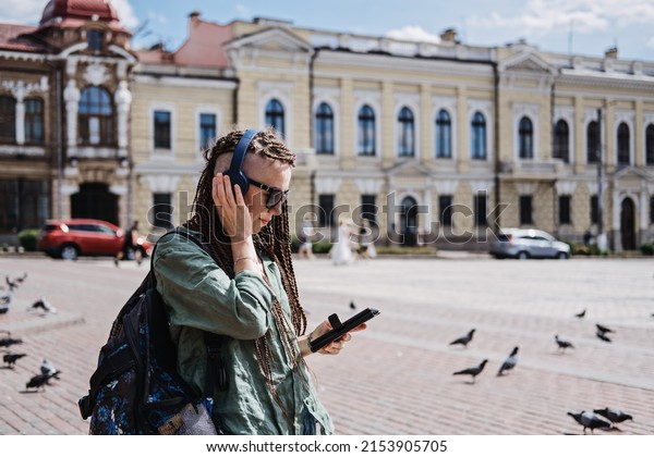 City Summer Vacation, urban trip with audio guide.
Audio Tours and Exploring new places. Hipster woman traveler with
dreadlocks headphones and cell phone use audio guide and Audio
Tours app