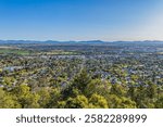 The city of Tamworth, famous for folk music festivals, sprawls below Oxley scenic lookout with the Melville range of mountains and blue sky in the background in New South Wales, Australia.