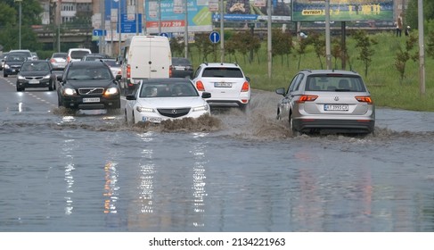 City traffic with cars driving on flooded street after heavy rain. Problems with road drainage system. Ivano-Frankivsk, Ukraine - June 12, 2021.