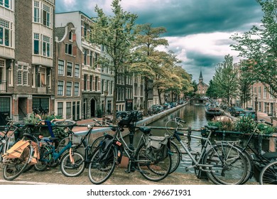 City view of Amsterdam canal and bridge with bikes, typical houses, church and boats, Holland, Netherlands.. Toning in cool tones