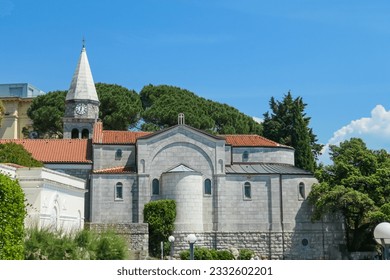 A city view of Opatija, Croatia. The main building is Saint Jacob Church. Tall trees around. Clear, blue sky above the city. The church's bell tower is the highest. Mediterranean spirituality. - Powered by Shutterstock