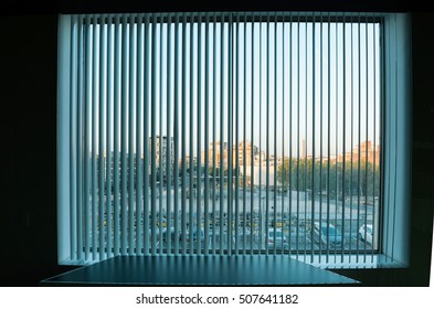 City view through the vertical blinds window decoration in interior of dark room