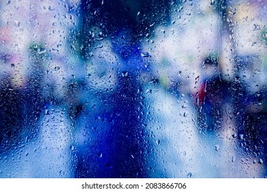 City View Through A Window On A Rainy Night,Rain Drops On Window With Road Light Bokeh, City Life In Night In Rainy Season Abstract Background. Focus On Drops On Glass