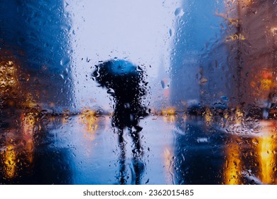 City view through a window on a rainy night,Rain drops on window with road light bokeh, City life in night in rainy season abstract background. Focus on drops on glass - Powered by Shutterstock