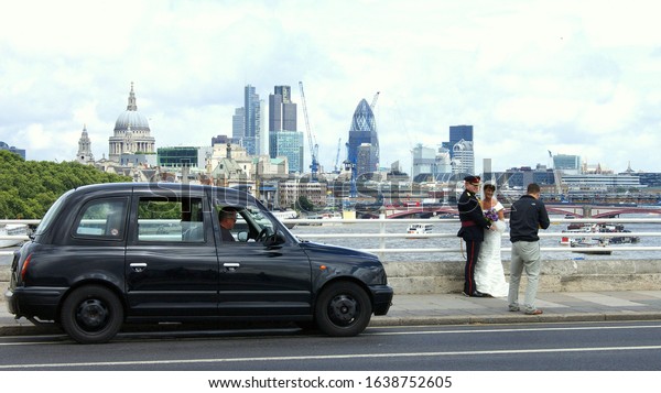 City of Westminster, London, UK - July 16, 2011:\
Black taxi cab, Army officer and a bride having photoshoot on\
Westminster Bridge