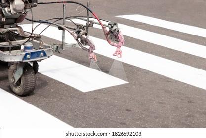 City Workers Paint Crosswalk Lanes On The Road With Painting Machine. Close Up.