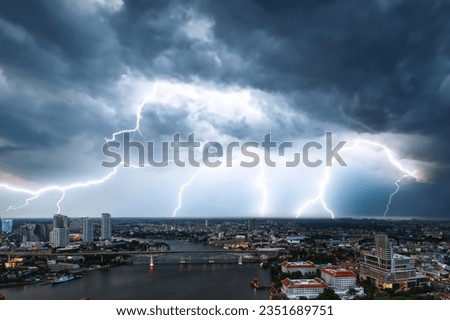 Cityscape along the Chao Phraya River in the city of Bangkok,phenomena of the atmosphere,weather with thunderstorm,overcast of the sky,strong winds,heavy rain and lightning,stormy weather,rainy season