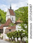 Cityscape with church and plane trees in picturesque village Saint-Ursanne in canton Jura destrict Porrentruy in Switserland