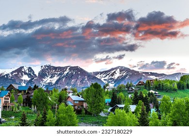 Cityscape of Crested Butte village small mountain town in Colorado in summer with dark morning sunrise clouds and chalet wooden houses on hills with green Aspen trees - Powered by Shutterstock