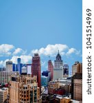 Cityscape of Detroit Michigan just after sunrise. Historical architecture, business buildings, apartments, skyscrapers and other structures in foreground. Background of open blue sky and clouds.