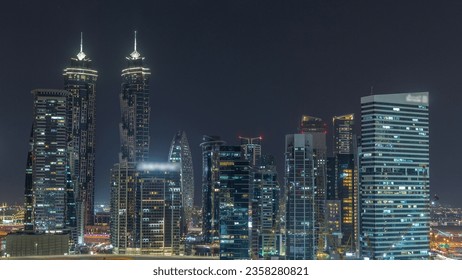Cityscape with illuminated skyscrapers of Dubai Business Bay and water canal aerial night timelapse. Modern skyline of residential and office towers on waterfront. Cranes working on construction site - Powered by Shutterstock