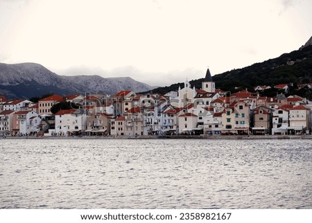 Cityscape image of Baska village, popular touristic destination on  Krk Island in Croatia, Europe. Evening in a port on the Adriatic sea, mountains in the background.