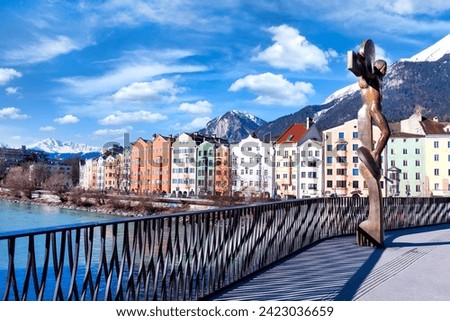 Cityscape of Innsbruck city center with beautiful houses, river Inn and river bridge with sculpture ,Tyrolian Alps, Austria, Europe
