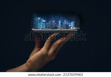 Cityscape intelligent building ,hold smart phone for build and make your smart city on hand. Futuristic urban hologram screen in concept of virtual internet of things and global network connection.