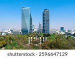 Cityscape of Mexico City, featuring Paseo de la Reforma with skyscrapers: Torre Reforma and Torre BBVA. In the foreground is the Chapultepec Park and the the Monumento a los Niños Héroes