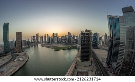 Cityscape panorama of skyscrapers in Dubai Business Bay with water canal aerial day to night transition. Modern skyline with towers and waterfront after sunset. A center of international business