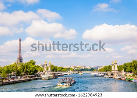 Cityscape of Paris, France, with a bateau-mouche cruising on the river Seine, the Alexandre III bridge, the Eiffel tower on the left and the Chaillot palace in the distance by a sunny summer day.