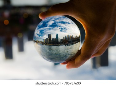 Cityscape Photography In A Clear Glass Crystal Ball With Dramatic Clouds Sky.