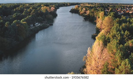 Cityscape At River Shore Aerial. Autumn Nobody Nature Landscape. Colorful Leafy Trees Forest At Sun Day. Cottages At City Streets. Urban Buildings At Downtown Suburbs. Green Grass Valley Stream Shore