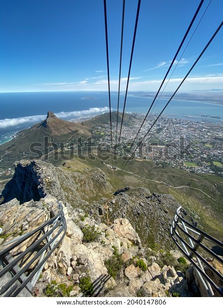 Cityscape scenic view\
of Cape Town, South Africa with cable of cable car in foreground\
against sea and blue\
sky