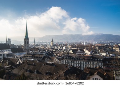 The cityscape of Zurich Switzerland with building roofs and church steeples under a cloudy blue sky